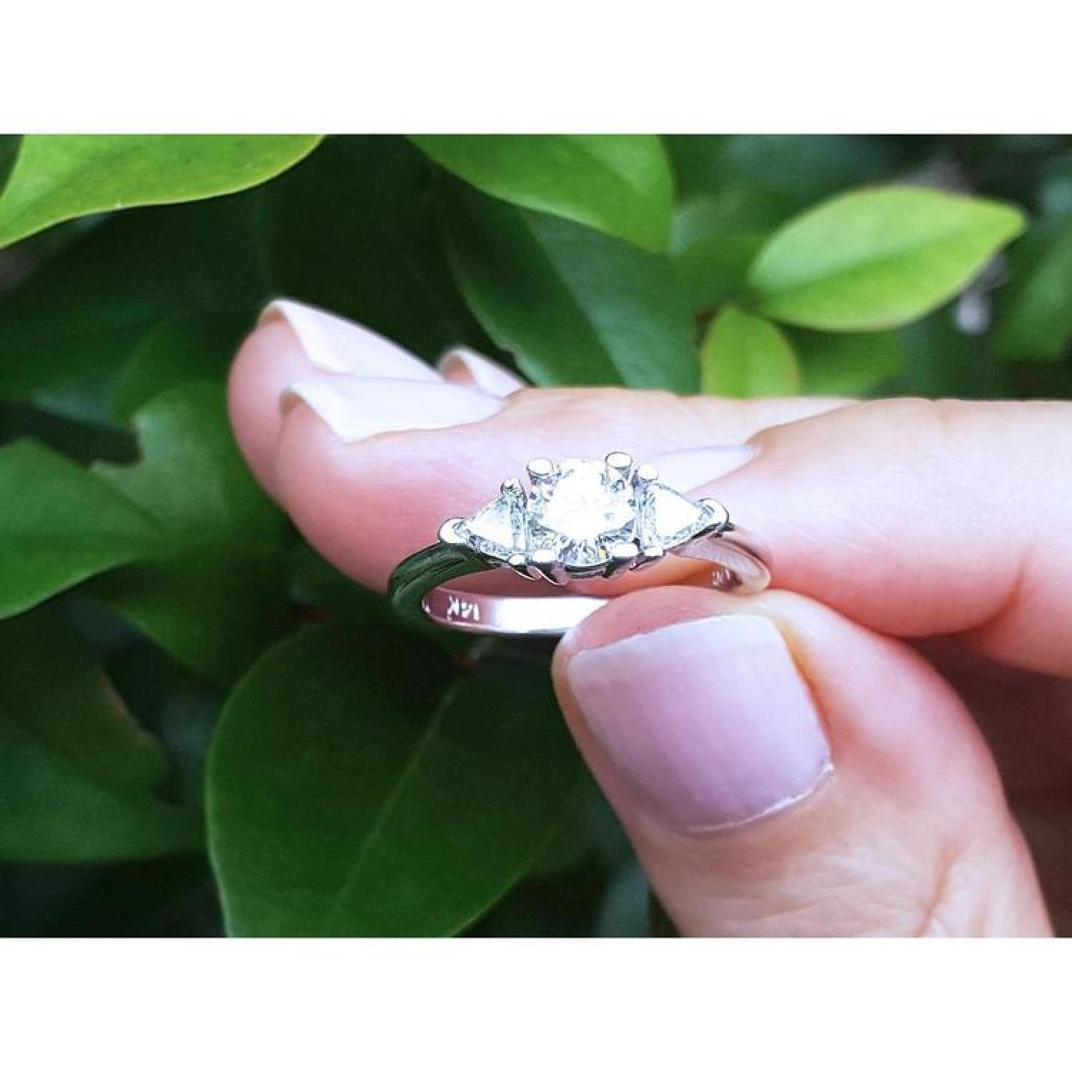14K white gold engagement ring with a round center diamond and two trillion side diamonds.