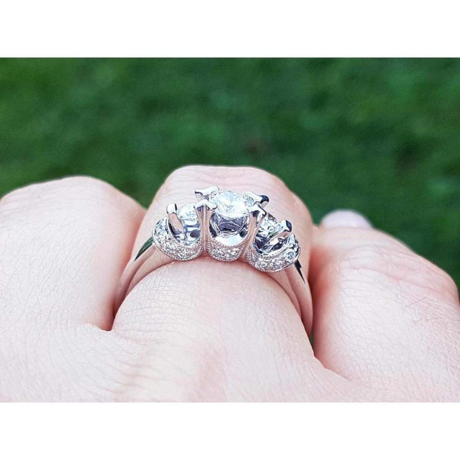 14K white gold three-stone engagement ring with round cut natural diamonds and pave set accents.