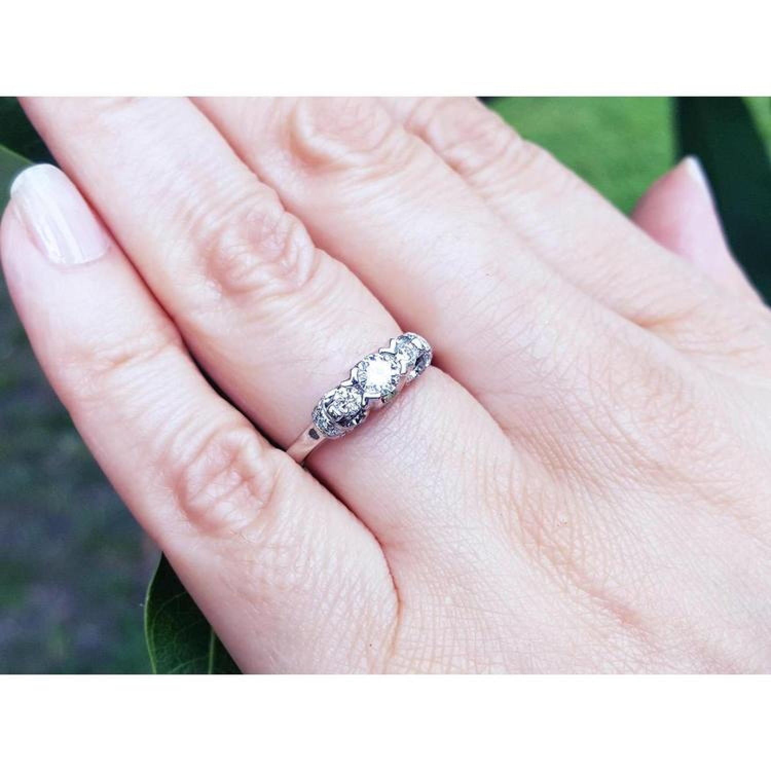 Round cut three stone diamond engagement ring in 14K white gold with pave set accent diamonds.