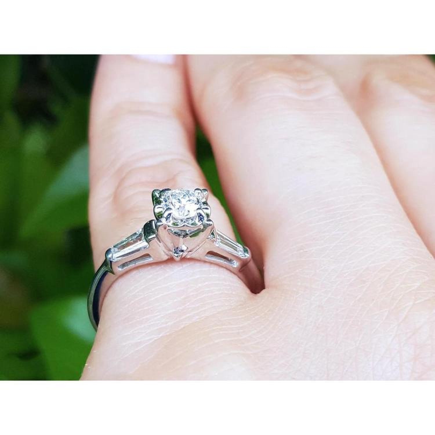 14k white gold engagement ring with a round diamond and two baguette side diamonds on a hand.
