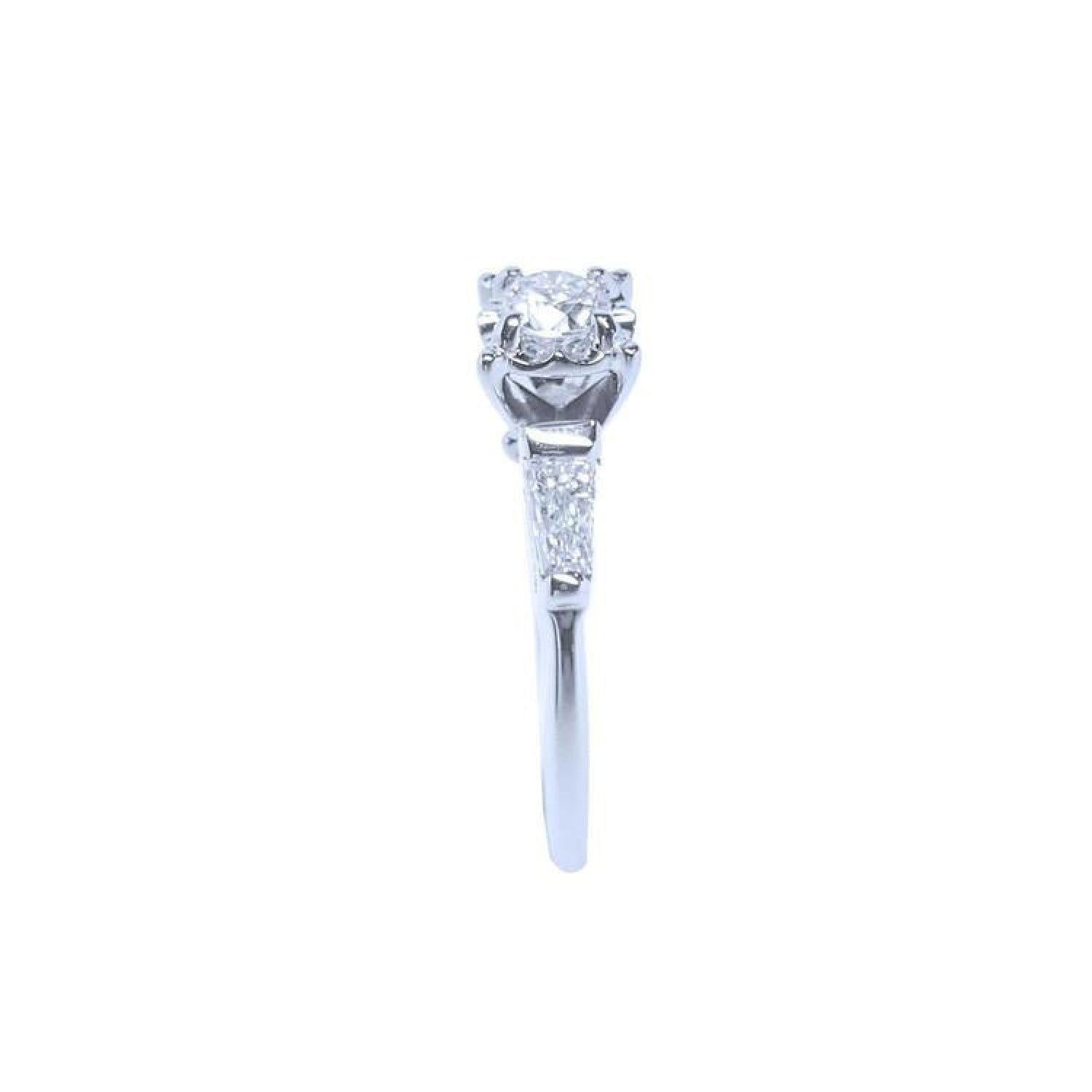 White gold engagement ring with a round central diamond and baguette side diamonds.