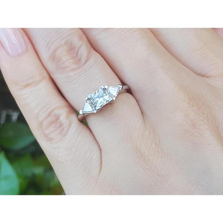 14K white gold ring with a princess cut center diamond and two trillion side diamonds on a hand.