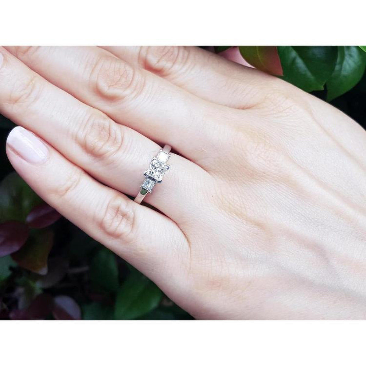Princess cut three-stone diamond ring in 14K white gold on a hand.