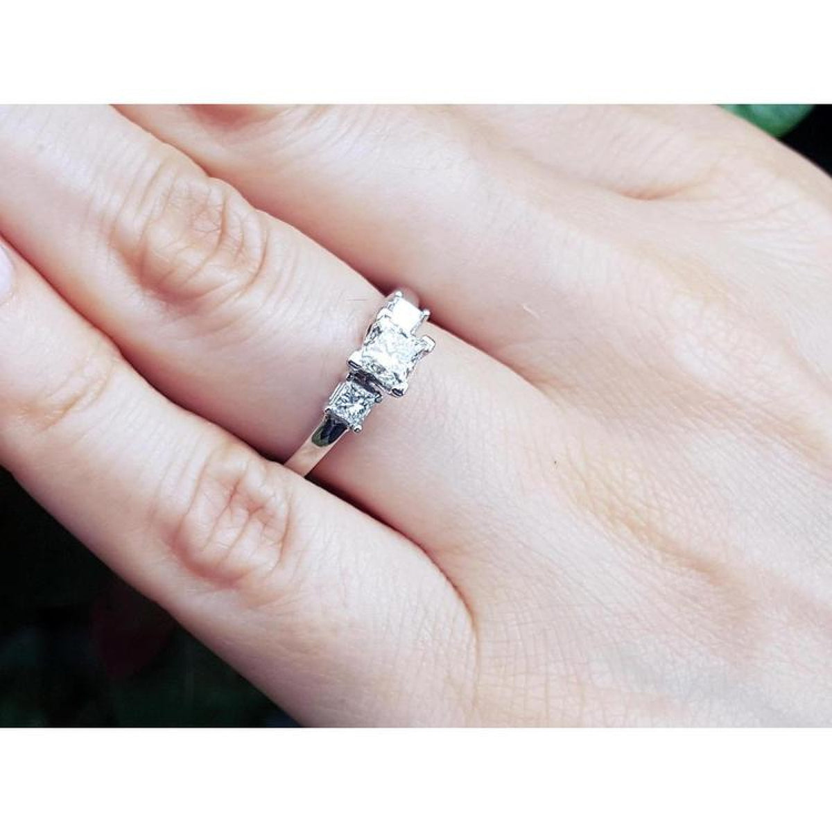 14K white gold three-stone ring with princess cut diamonds on a hand.