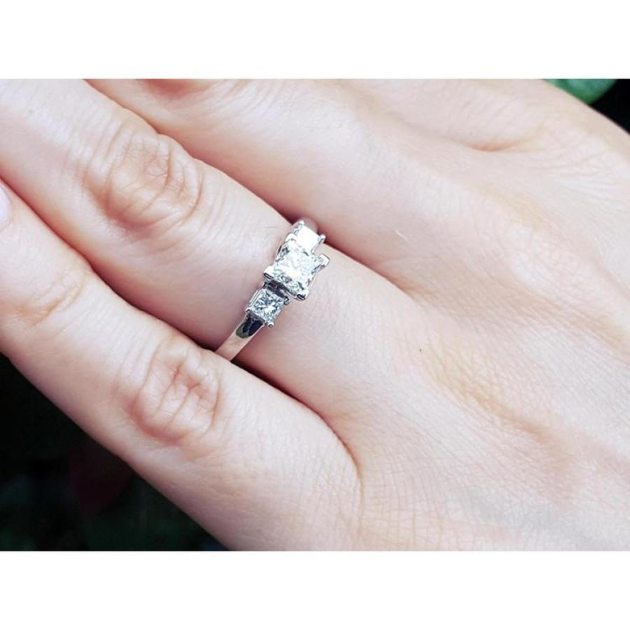 14K white gold three-stone ring with princess cut diamonds on a hand.