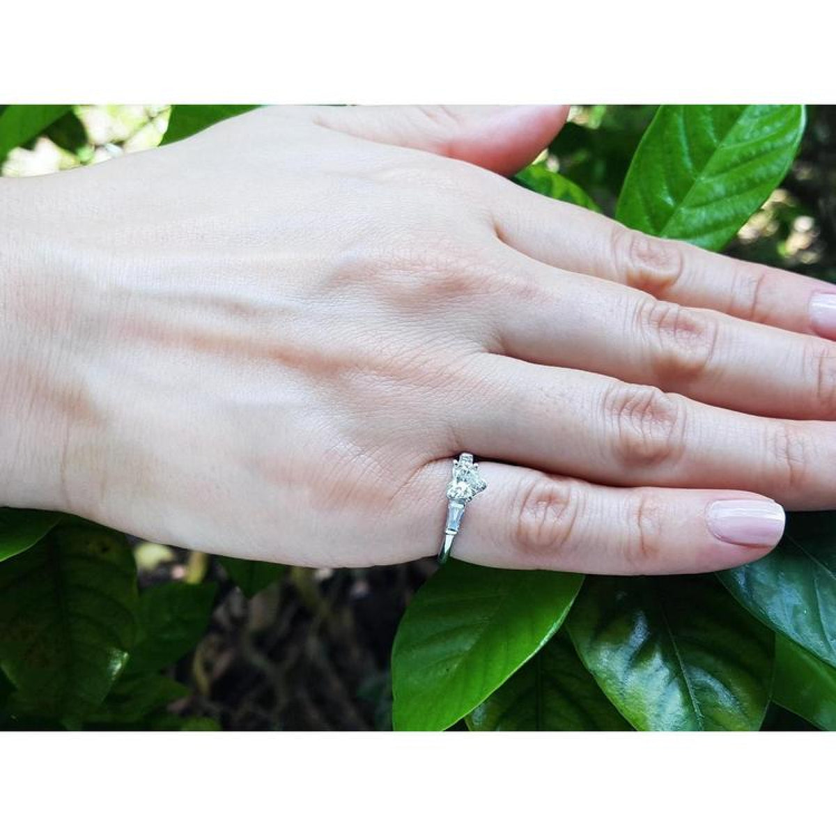 Heart cut diamond engagement ring with side baguette diamonds in 14K white gold on a hand.