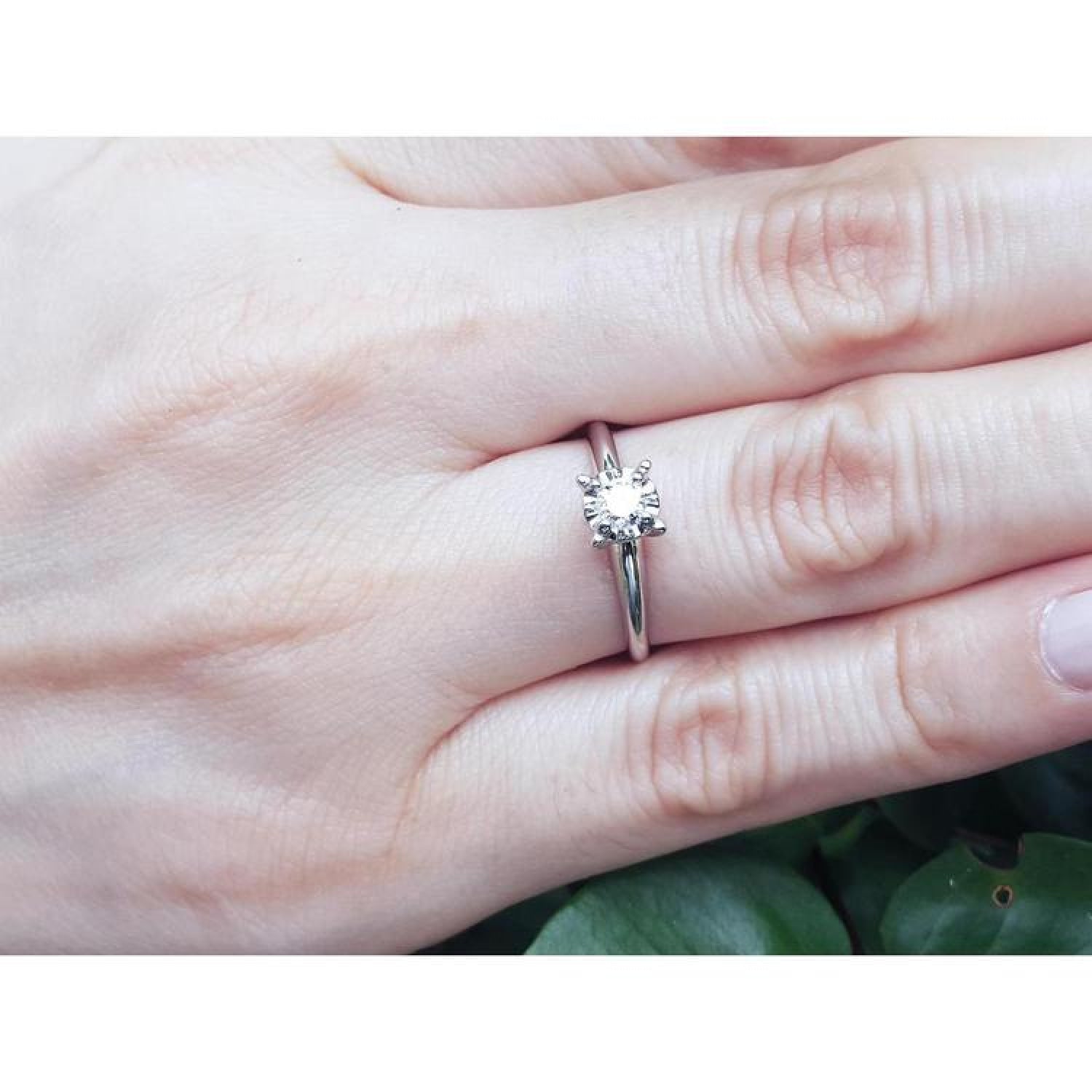 Round cut diamond solitaire engagement ring in 14K white gold on a hand.