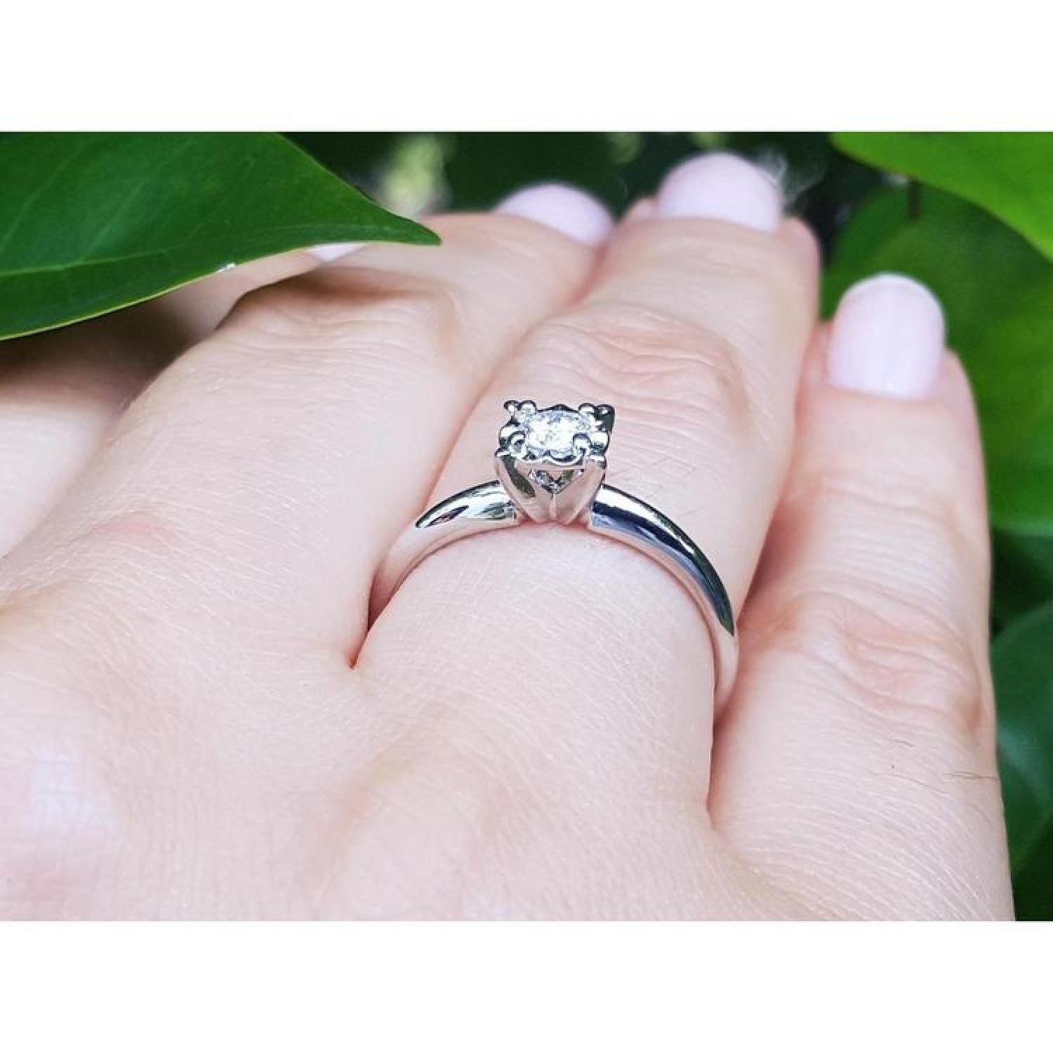 Round cut diamond solitaire engagement ring in 14K white gold on a hand.