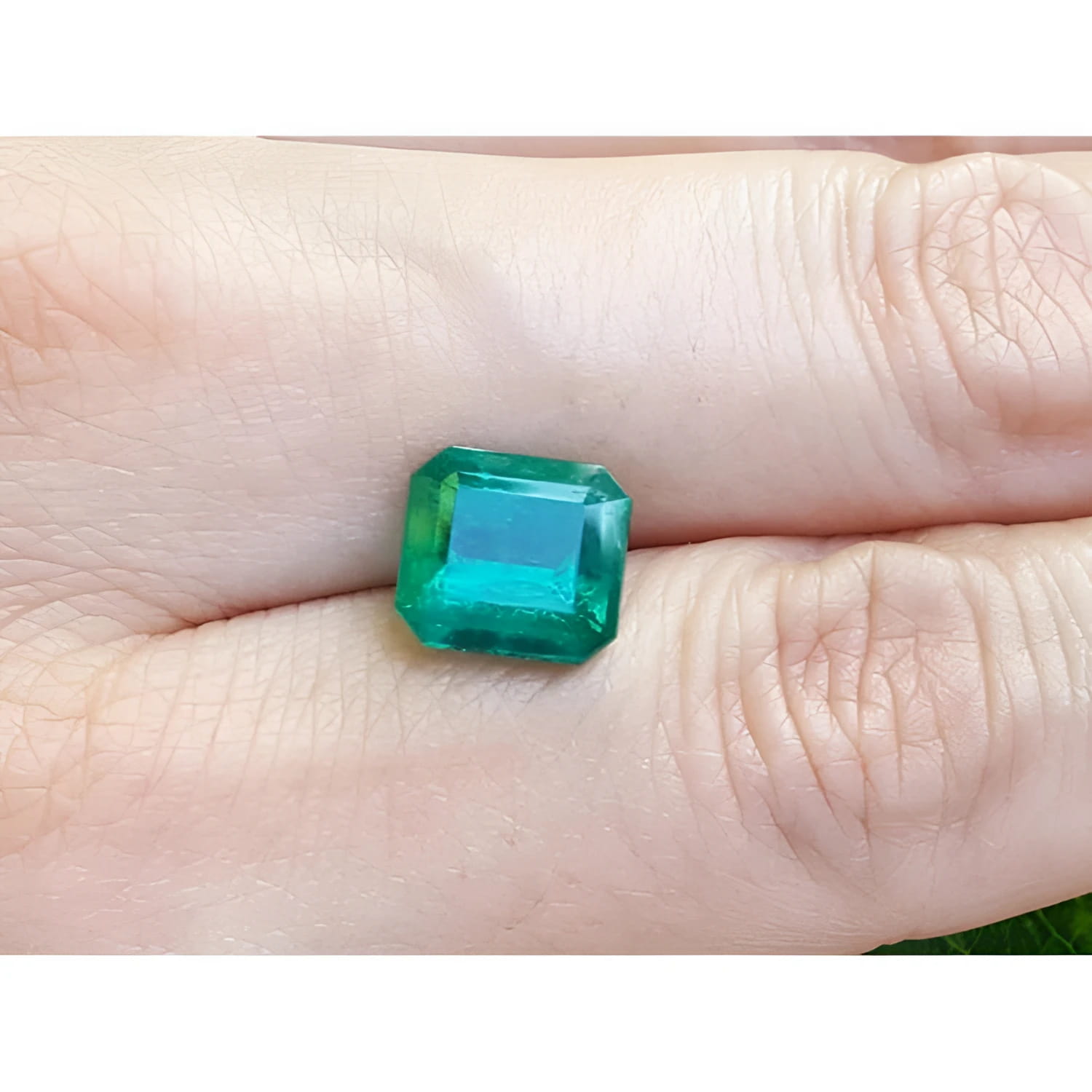 GIA certified 3.55 ct. emerald-cut Colombian emerald gemstone on a hand.