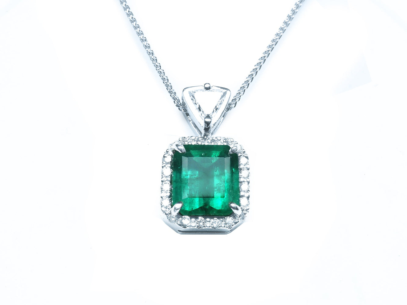 Encircled in a halo diamond a natural colombian emerald pendant square rectangular shape.