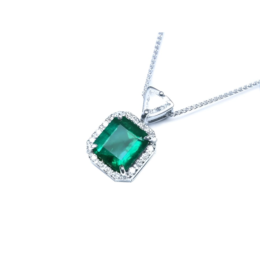 Emerald cut Colombian emerald pendant in 18K white gold with diamond halo and bail.