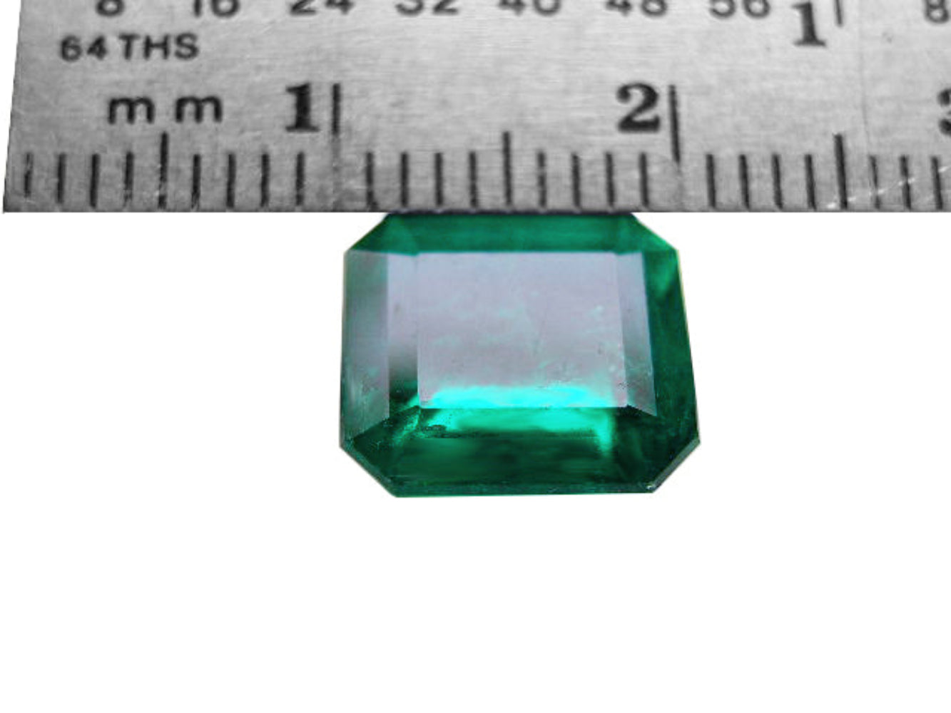 A natural colombian loose emerald with a ruler showing its size in millimeters.