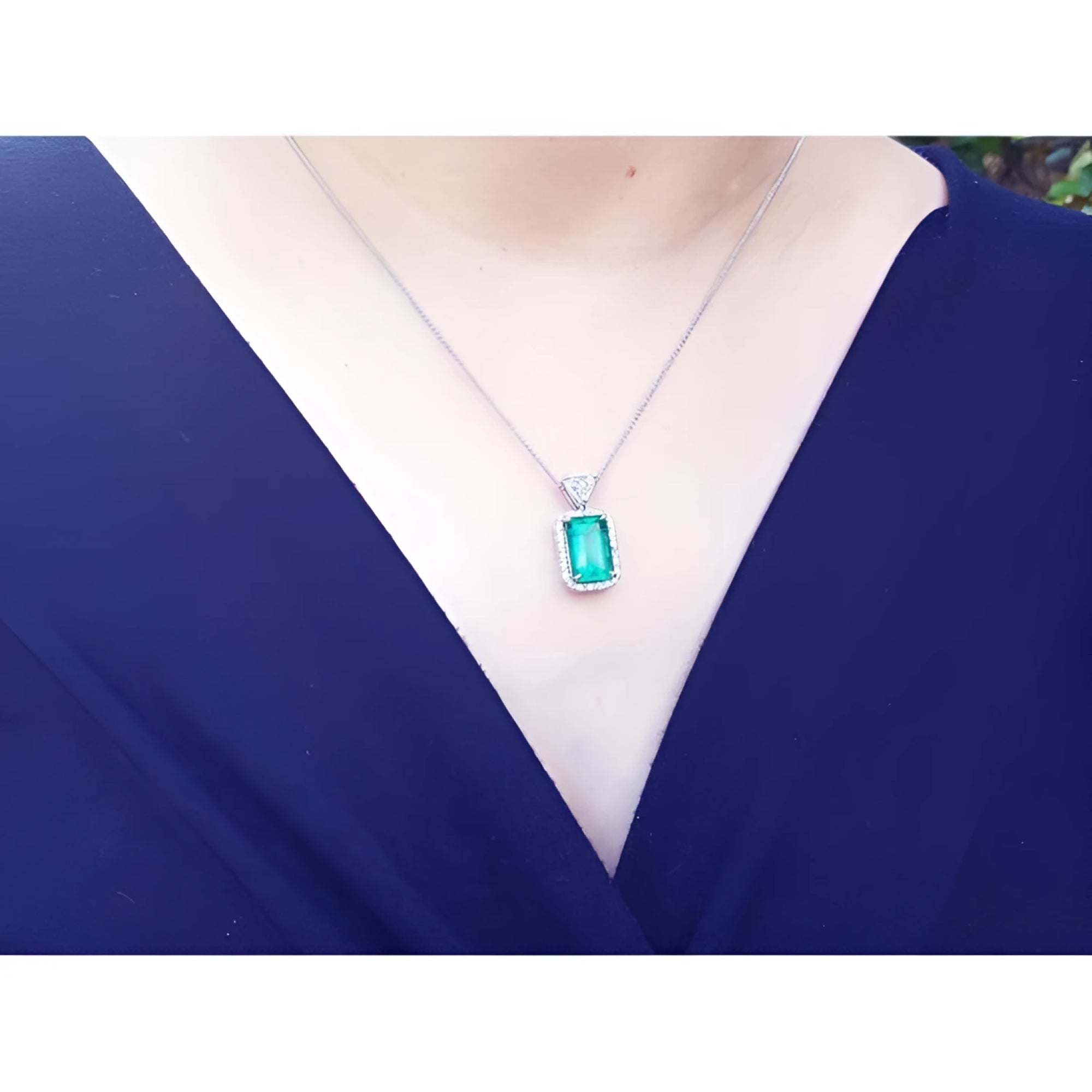 GIA certified Colombian emerald pendant with medium-deep green emerald cut gem, diamond halo, on 18K white gold chain.