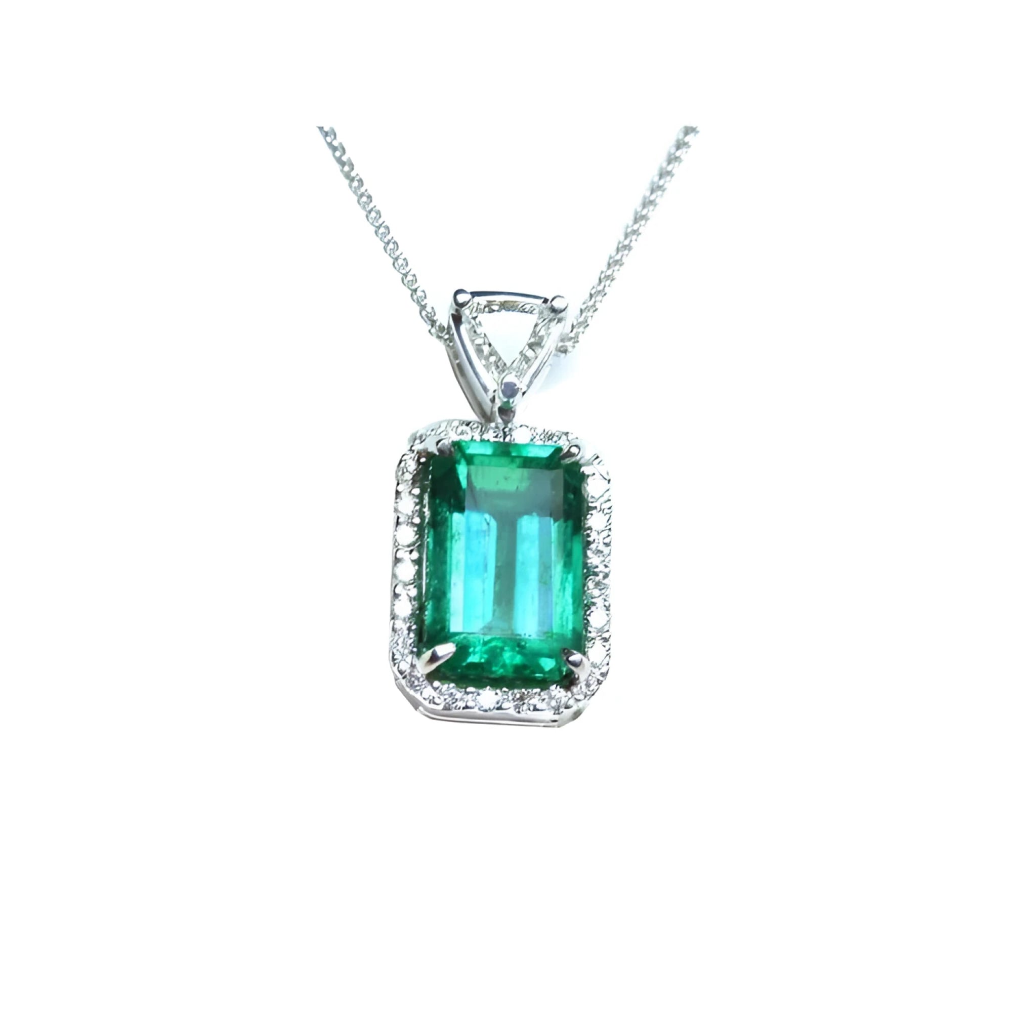 The topside of this certified natural emerald pendant shows the top bail slider with a trillion-cut diamond and the emerald with a halo diamond.