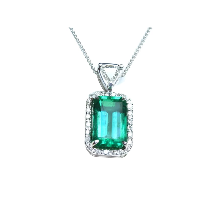 The topside of this certified natural emerald pendant shows the top bail slider with a trillion-cut diamond and the emerald with a halo diamond.