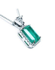 GIA certified 5.65 ct Colombian emerald pendant with medium-deep green emerald-cut gem and diamond halo in 18K white gold.