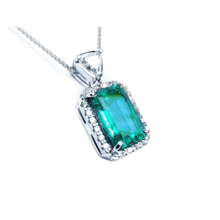 This GIA certified colombian emerald in this pendant is surrounded by a halo diamond, on the top bail a trillion-cut diamond.