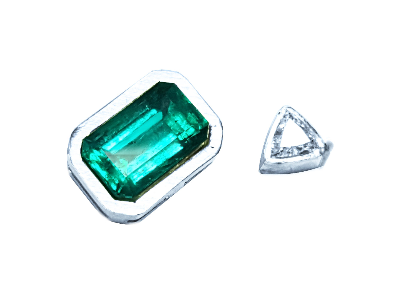 Green emerald and clear diamond on a white background showing the handcrafted setting on the rough.