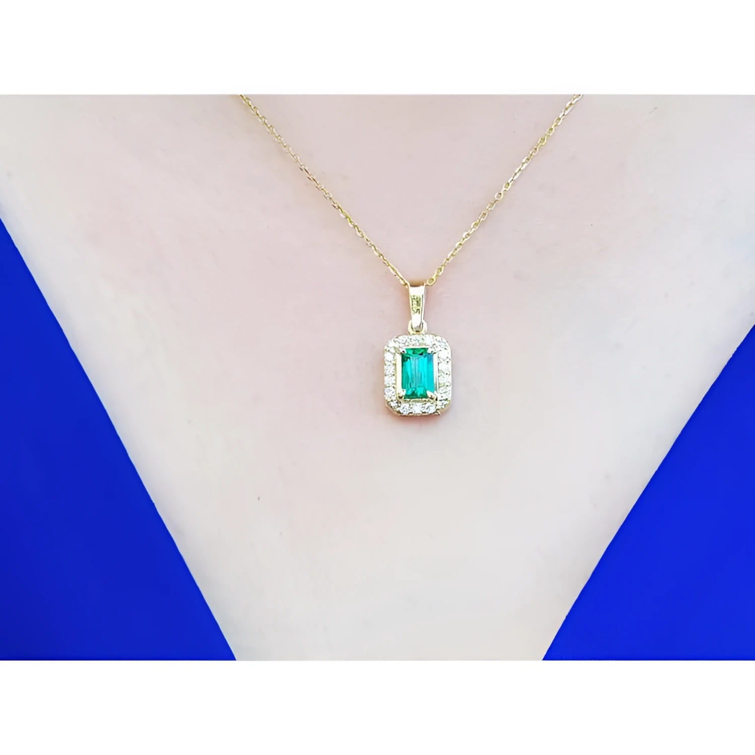 0.75 ct. GIA certified F1 Colombian emerald pendant with diamond halo in 18k yellow gold on a woman's neck.