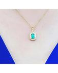 0.75 ct. GIA certified F1 Colombian emerald pendant with diamond halo in 18k yellow gold on a woman's neck.