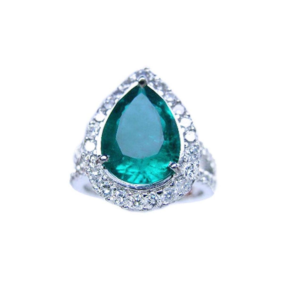 Ring with a emerald teardrop-shaped gemstone and diamond-studded band on a front position top view.