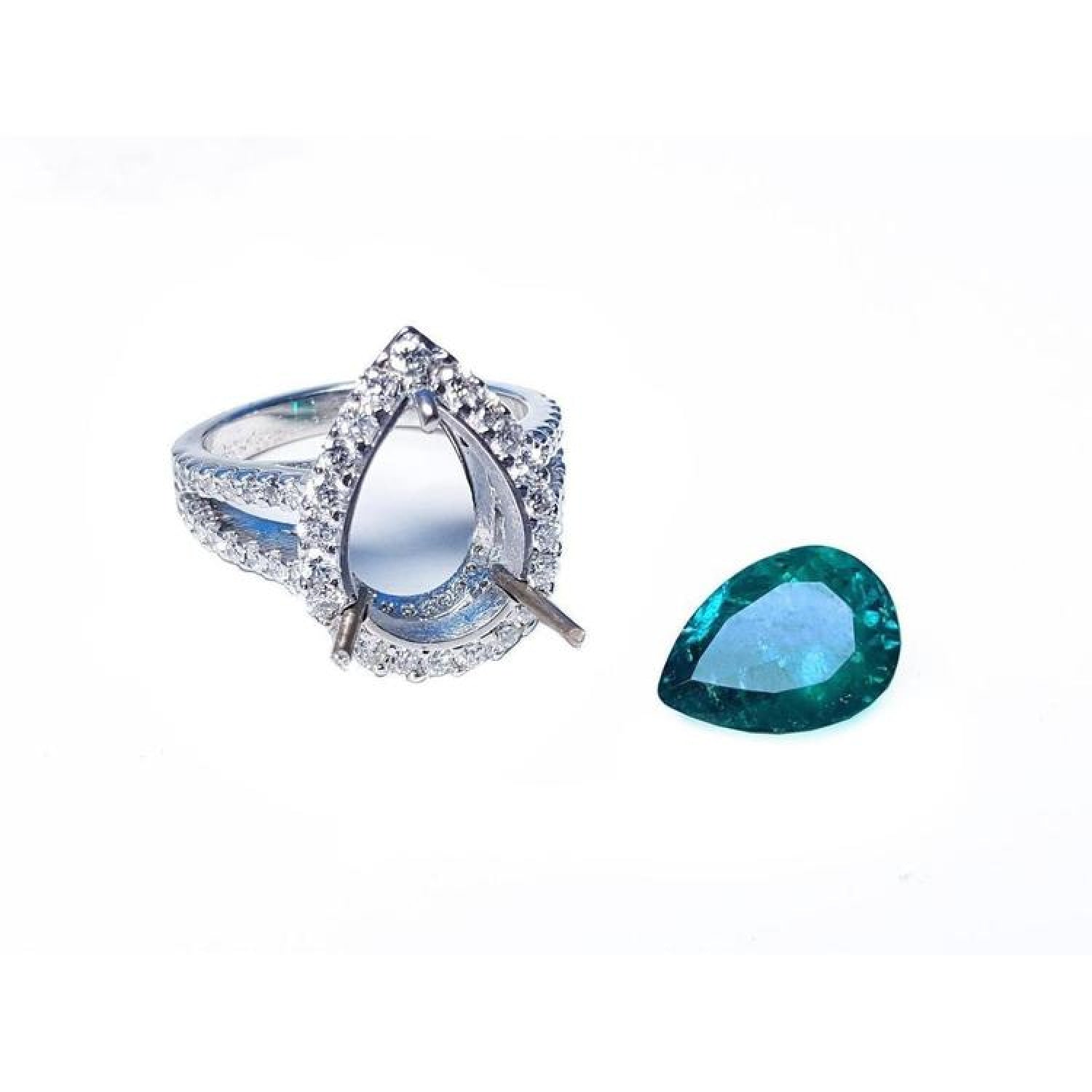 18K white gold ring setting with diamond halo next to a loose 4.02 ct pear-shaped deep bluish-green emerald.