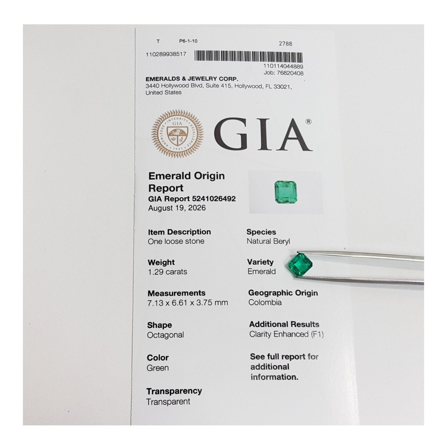 A GIA Emerald Origin Report card for a loose green emerald stone, with a small green gemstone resting on the right side of the white paper.