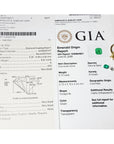GIA diamond grading report and emerald origin report with a gold ring featuring a green gemstone on a white background.