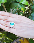 Esmeralda rectangular rodeada de diamantes en anillo de compromiso