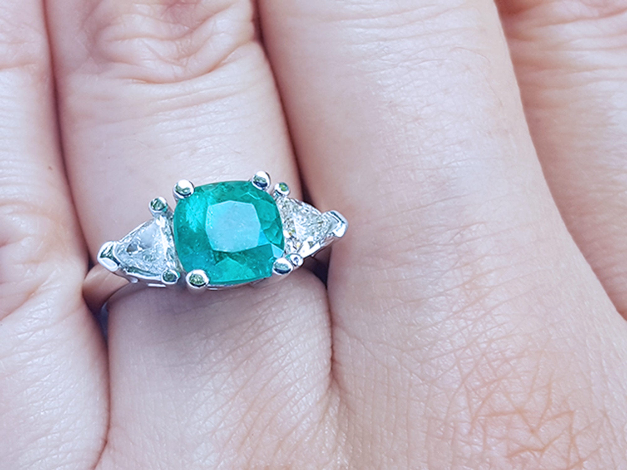 Women's cushion cut emerald and trillion side diamonds ring