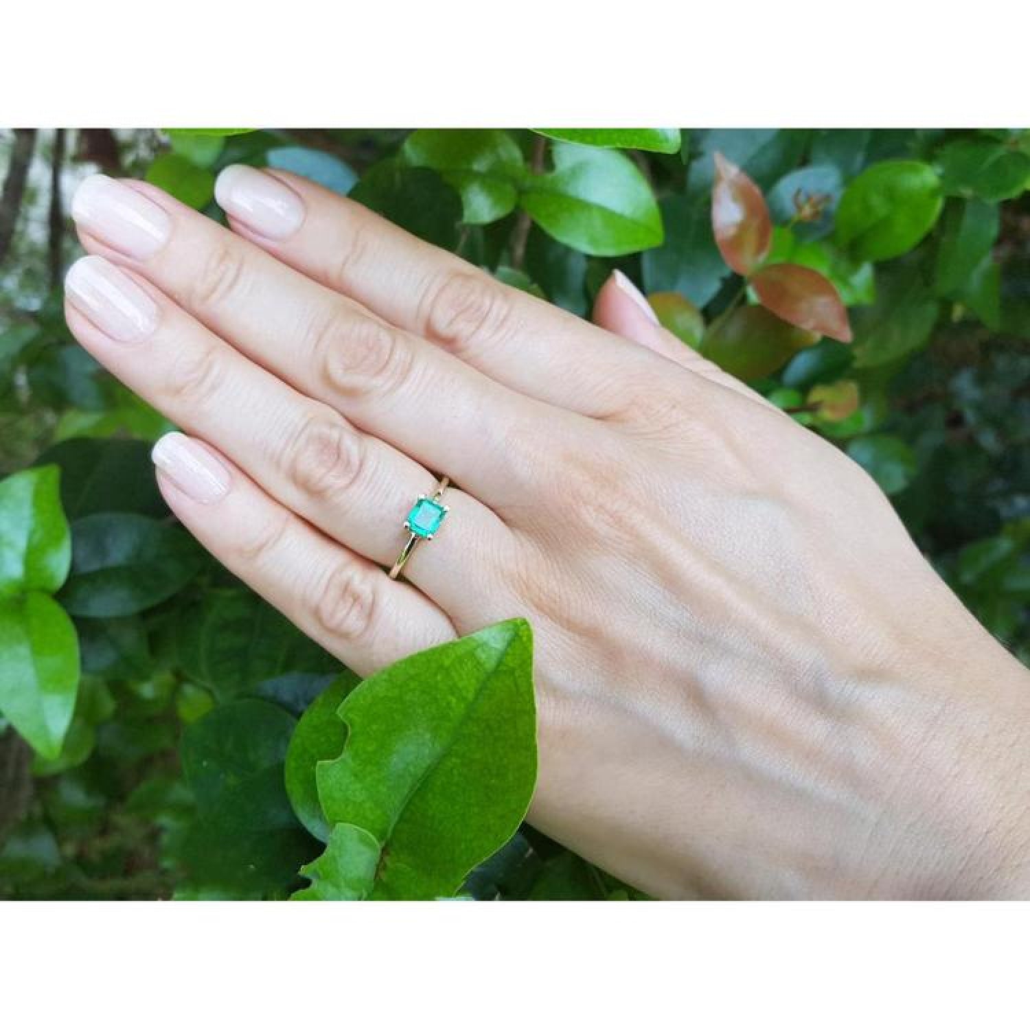 Minimalist 14K yellow gold ring with a petite, square-cut natural Colombian emerald on a hand.