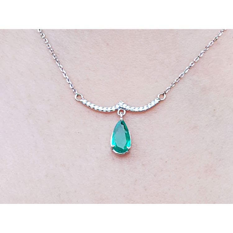 14k white gold necklace natural Colombian emerald dangling from a wavy central bar with diamonds pave set