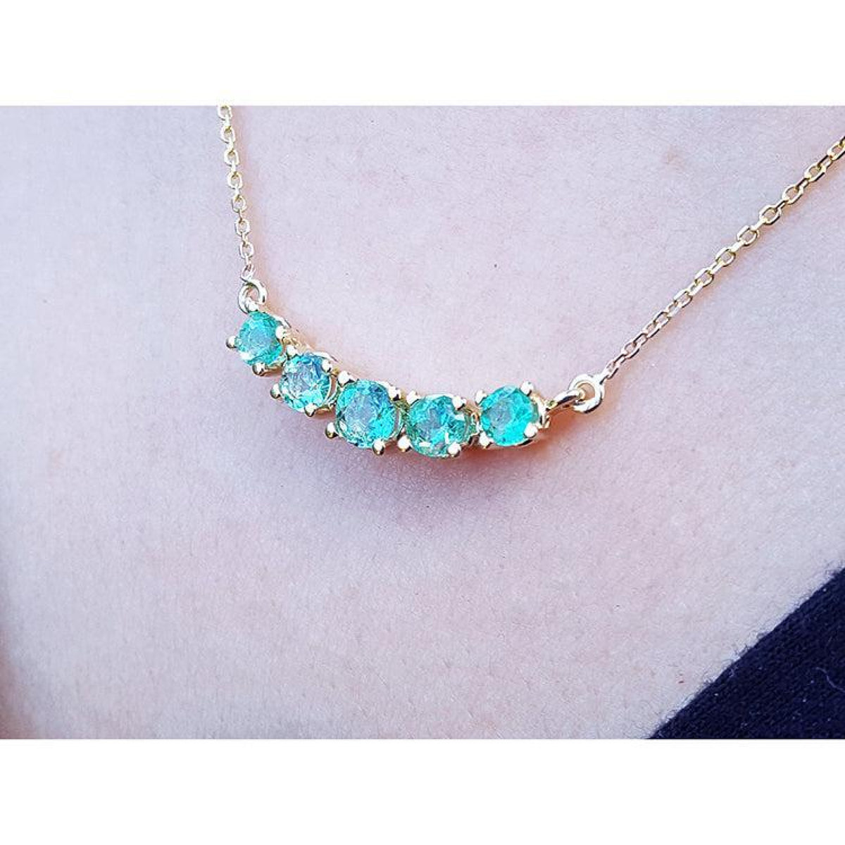14K gold necklace with five sparkling round-cut medium light green Colombian emeralds.