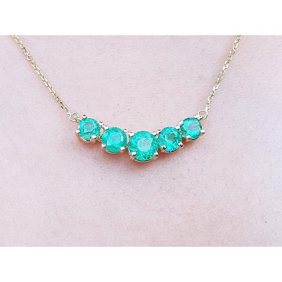 14K gold necklace with five round, medium green Colombian emeralds in elegant basket settings.
