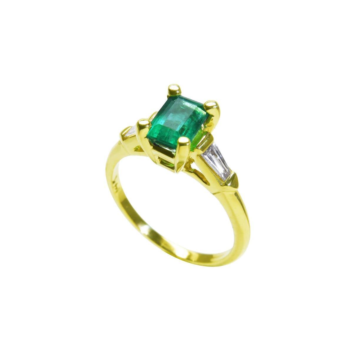 The tilted position of this emerald ring shows the top gemstone, side diamond and band profile.