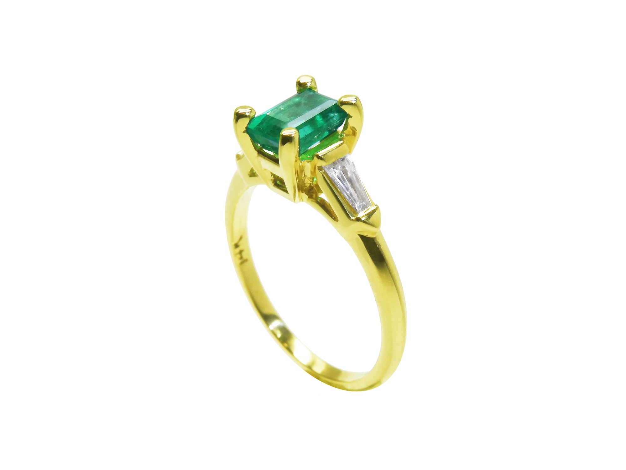 A yellow gold emerald ring on a white background.