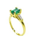 A yellow gold emerald ring on a white background.