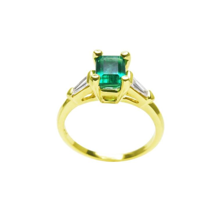 14K yellow gold ring with a vibrant emerald-cut emerald and baguette side diamonds.