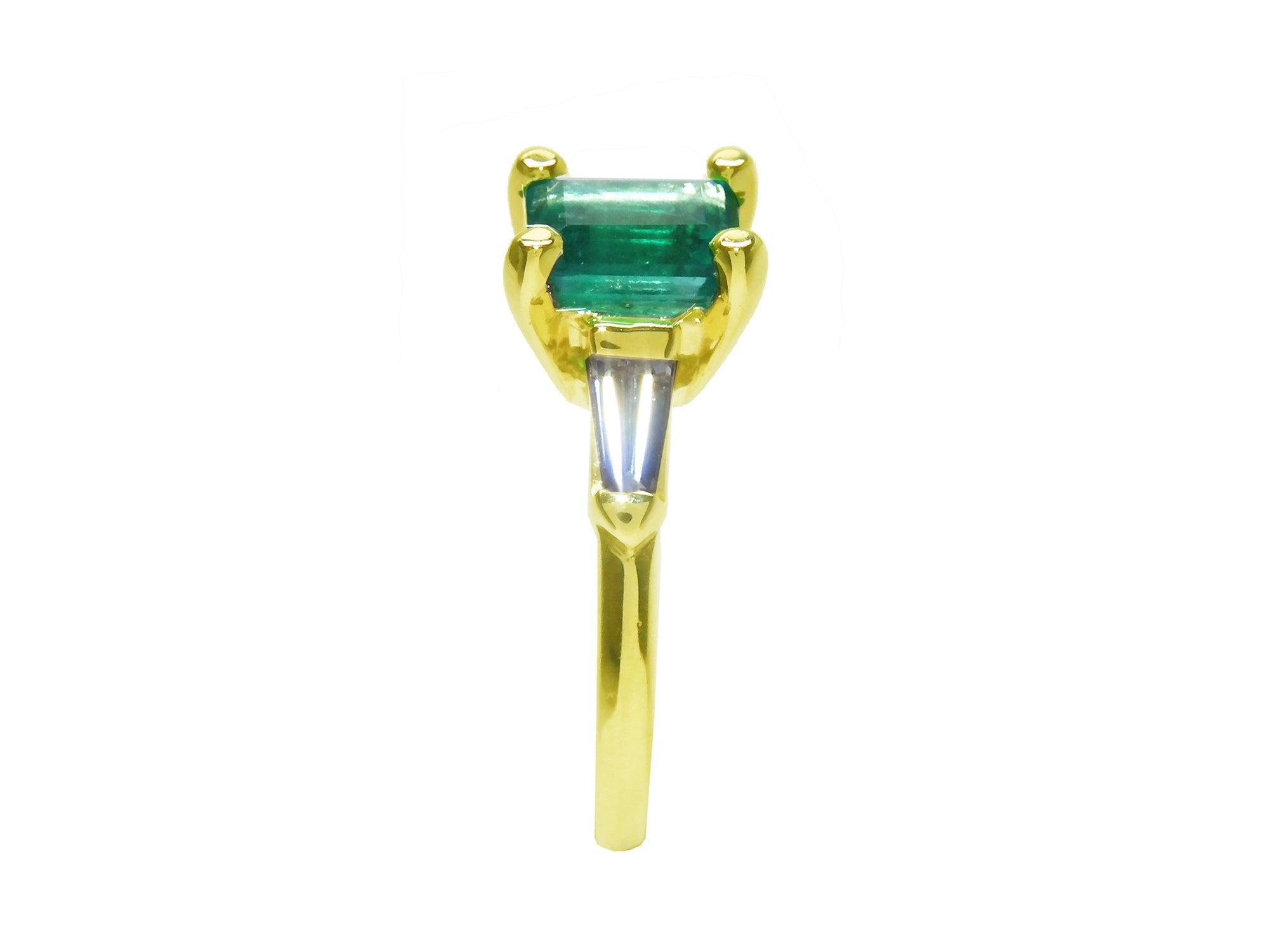 The side profile of this emerald ring displays the top setting, side tapered baguette diamond and band ring.