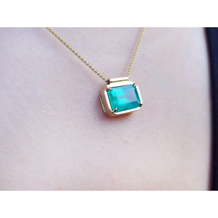 slider solitaire necklace with a Colombian emerald east west orientation set in a handmade setting in 18k yellow gold