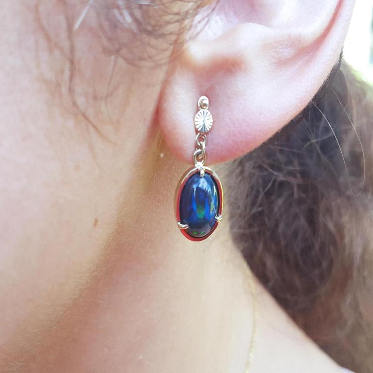 Ethiopian Welo black opal oval drop earrings with bluish-green and red-orange fire, set in 14K yellow gold.