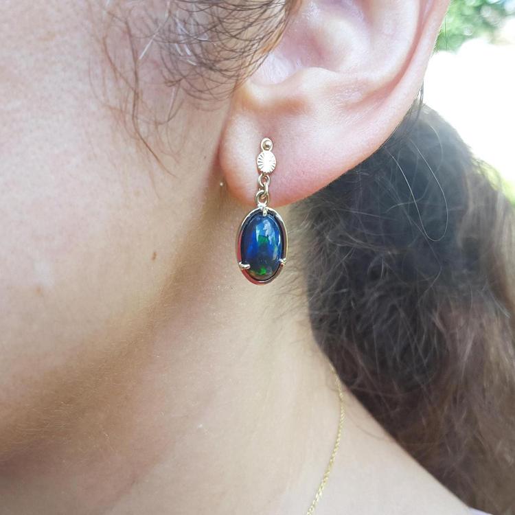 Ethiopian Welo black opal earrings with bluish-green and red-orange colors, set in 14K yellow gold.