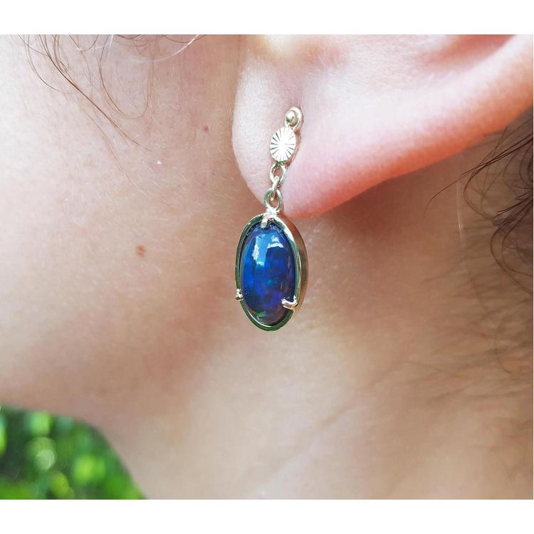 Ethiopian Welo black opal earrings with bluish-green and red-orange colors, set in 14K yellow gold.