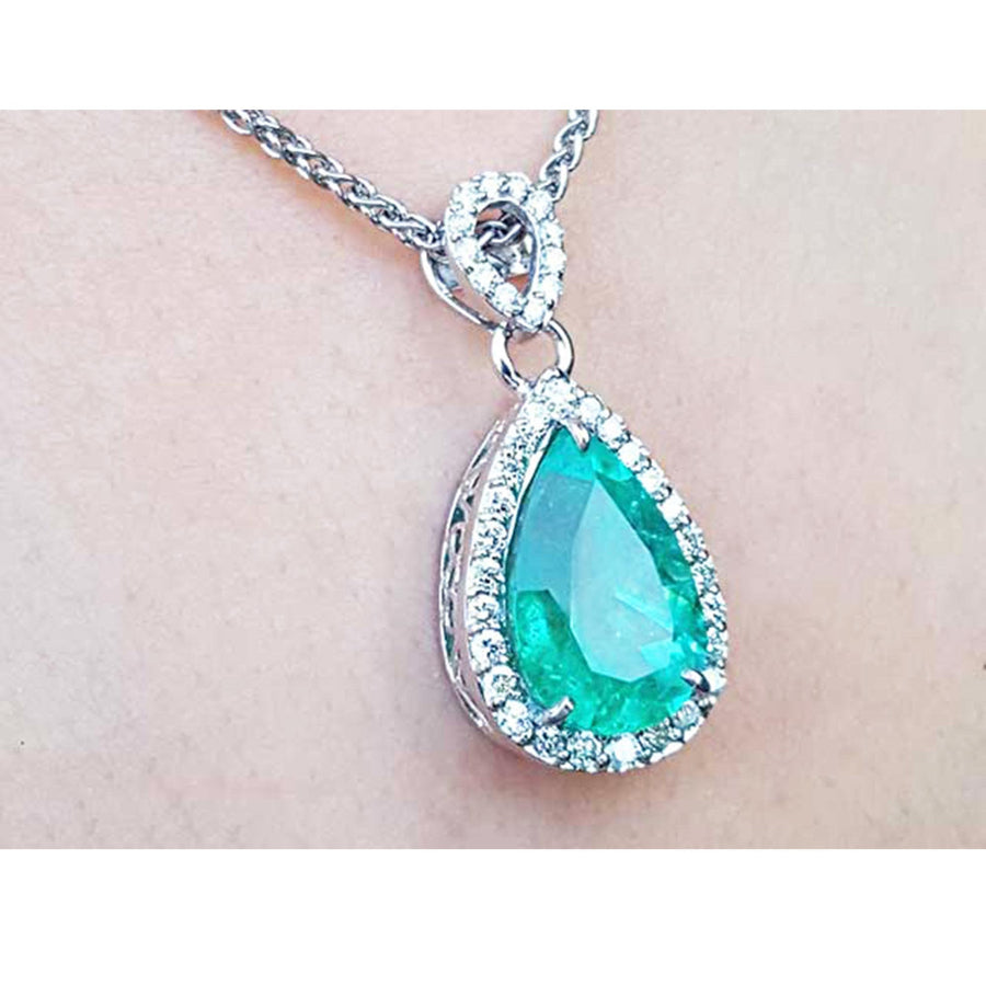 14k white gold pendant with a natural colombian emerald surrounded in a halo of genuine diamonds.