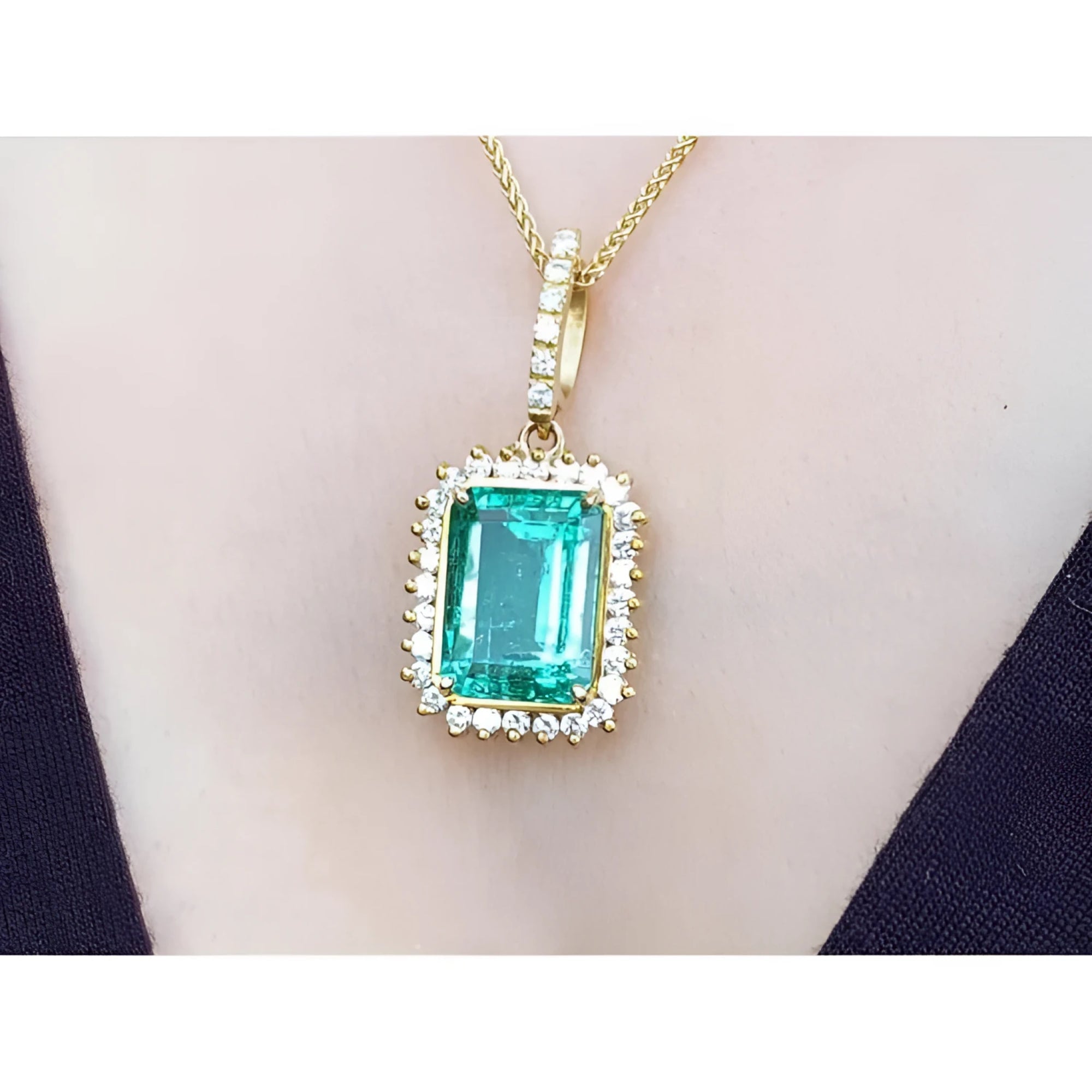 Emerald-cut emerald pendant with halo diamonds in 18K gold, worn on a necklace.