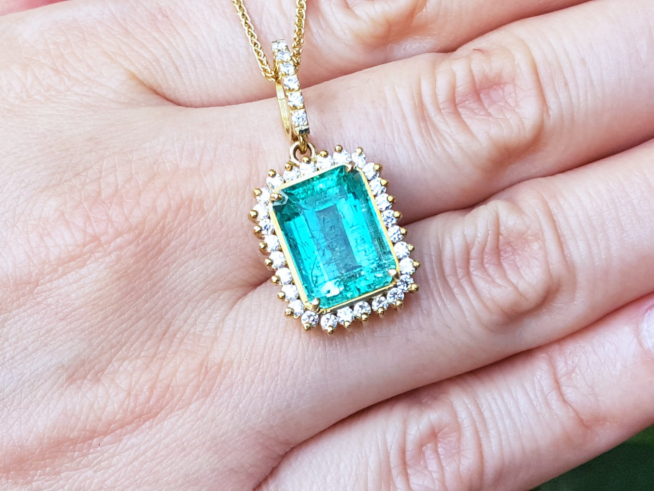 Gold pendant with a natural colombian emerald held in a hand.