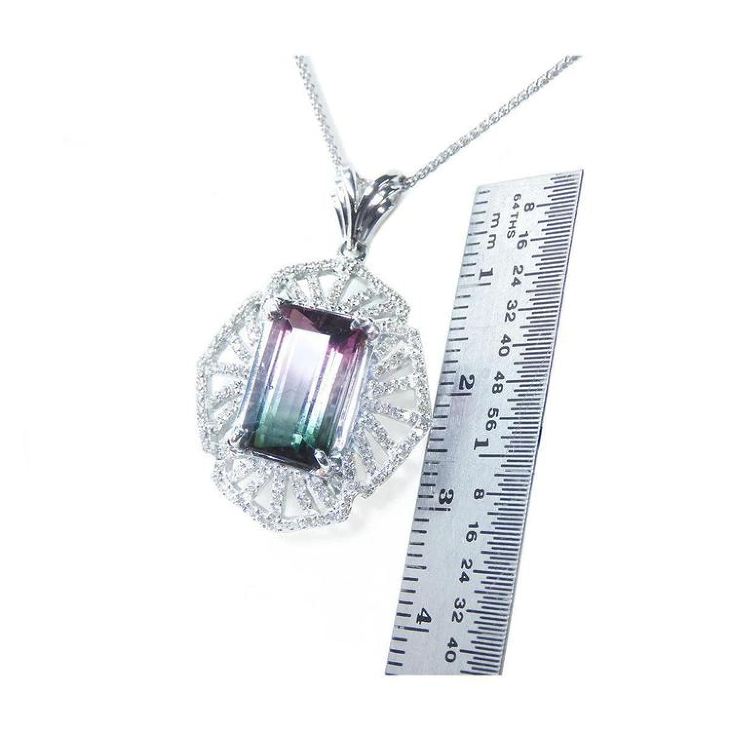 Emerald cut watermelon tourmaline pendant with diamonds on a 14K white gold chain, next to a ruler.