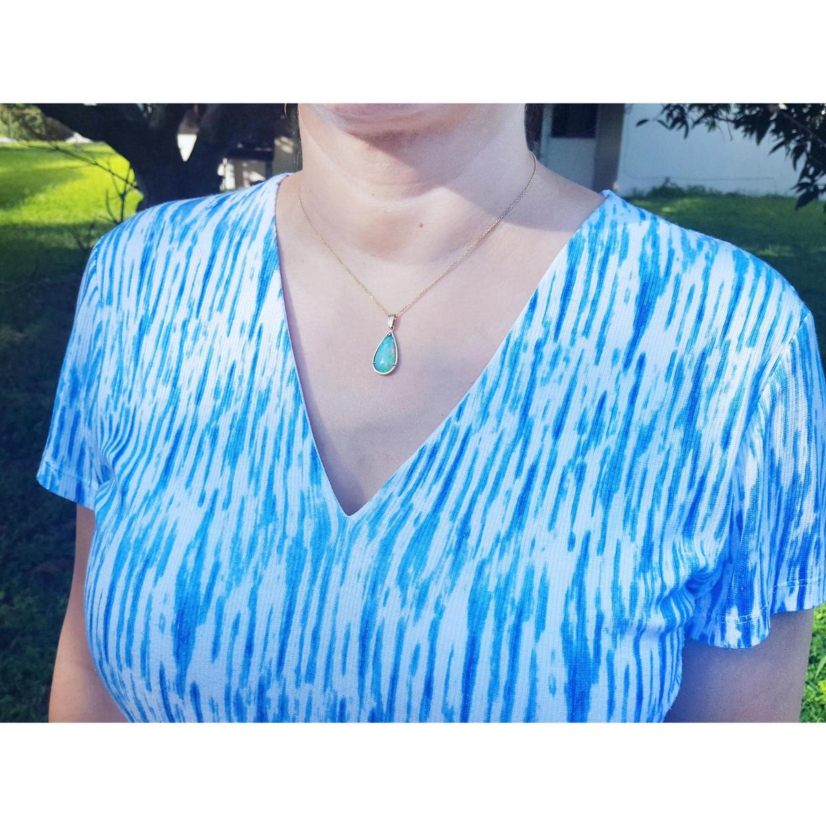 Person wearing a blue and white tie-dye shirt with a necklace outdoors.
