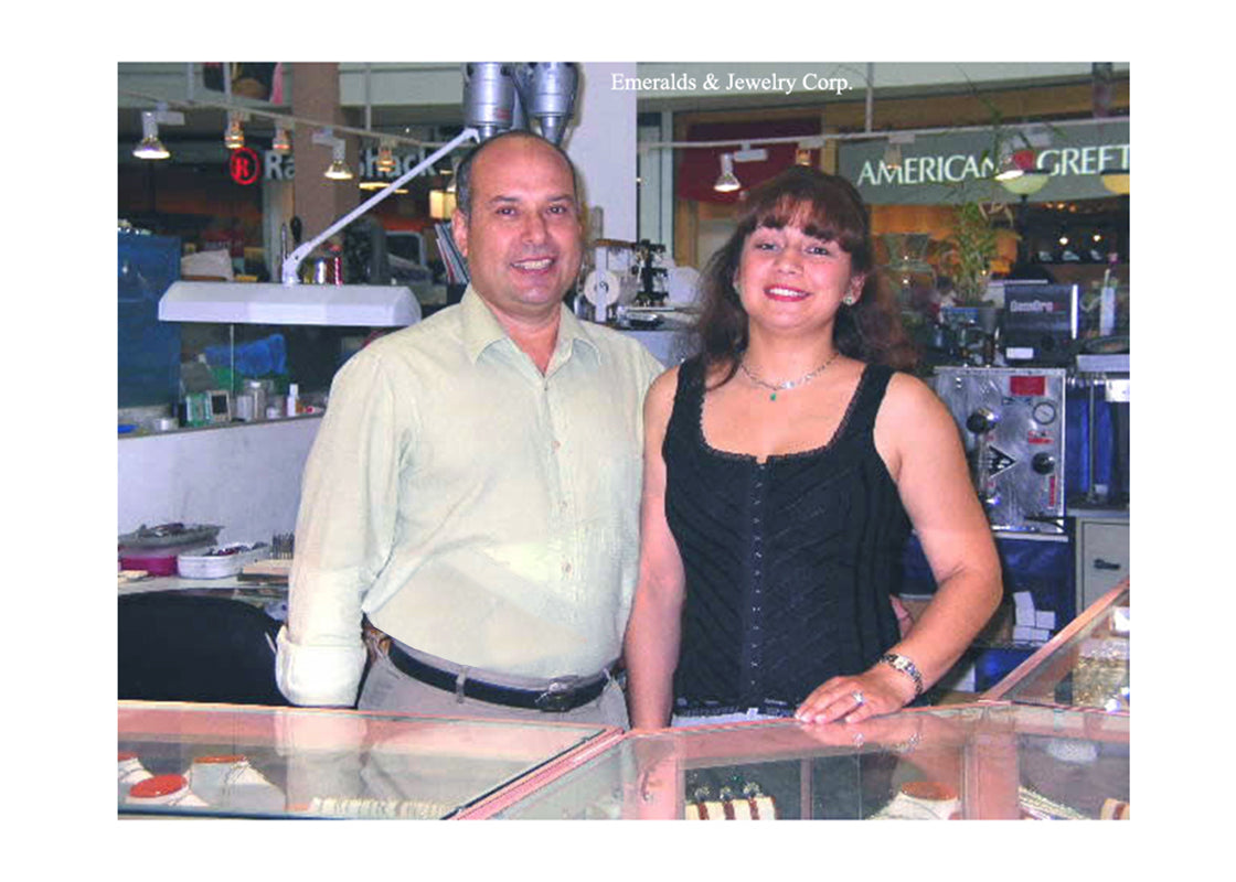 Two people standing behind a counter in a store with various items on shelves.