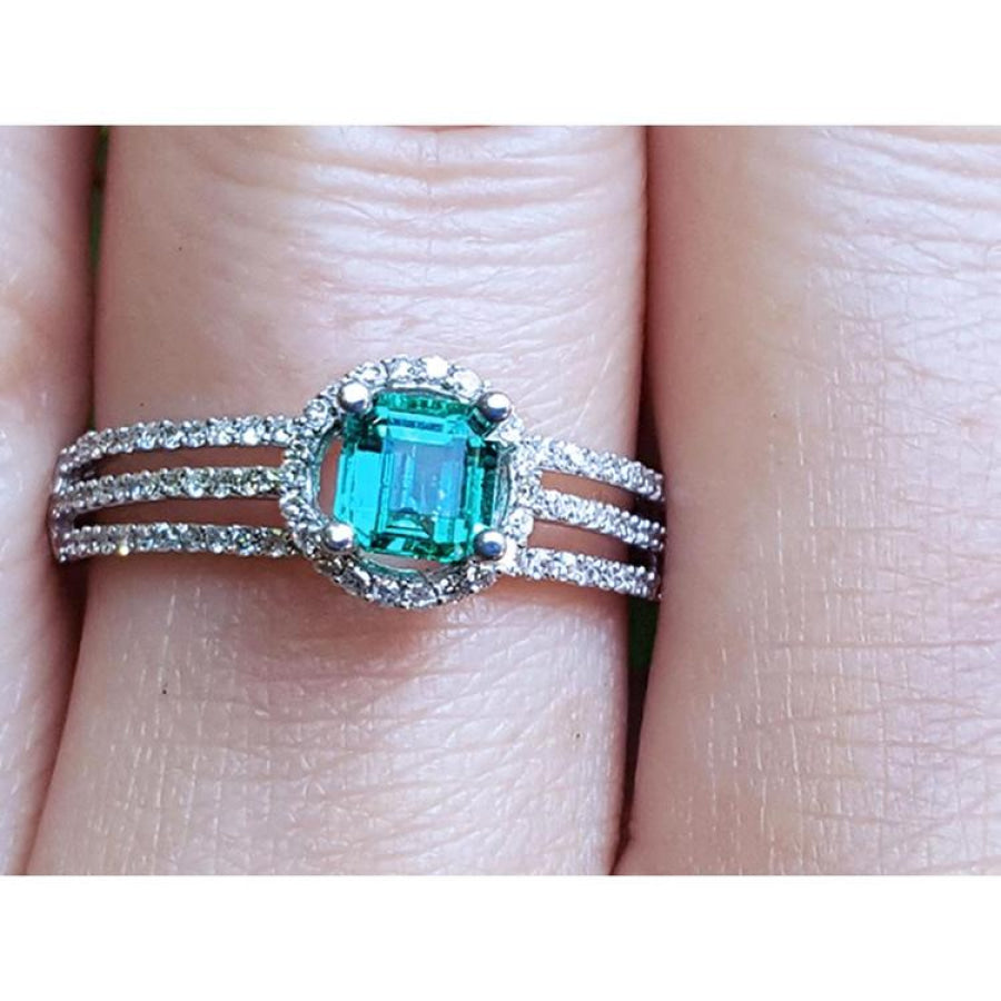 Emerald engagement ring with halo diamonds and three rows of diamonds on a 14K white gold band.
